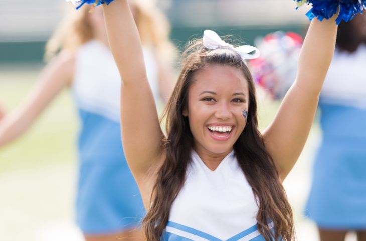 Cheerleader with arms up smiling